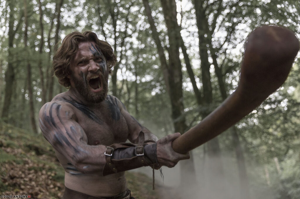 roman man in action with wooden club part of movie called caledonia on imdb